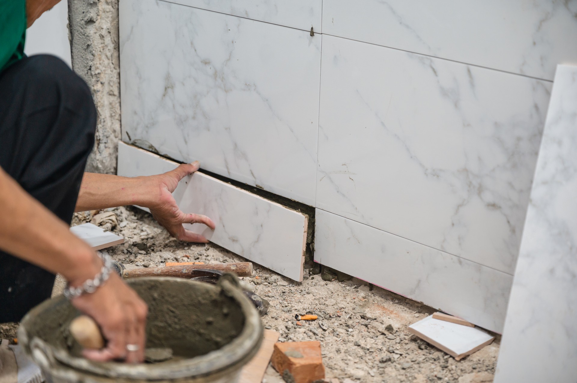 Male tiler using trowel laying marble tile with cement in bathroom. Housing development, improvement renovation